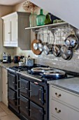 THE COACH HOUSE,SURREY: COUNTRY KITCHEN WITH BLACK AGA AND TILED SPLASHBACK WITH SHELF AND HANGING POTS AND PANS. NEUTRAL DECOR