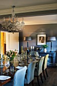 THE COACH HOUSE,SURREY: DINING ROOM. CHANDELIER BY INDIA JANE,CONSOLE TABLE & LAMPS BY MARGARET BOYD, DARK WOOD TABLE & FABRIC CHAIRS FROM HUDSON HOMES & INTERIORS.ENTERTAINING.