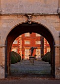 BURTON AGNES HALL, EAST YORKSHIRE: CHRISTMAS - THE ELIZABETHAN HOUSE SEEN THROUGH THE GATEHOUSE - YEW, TAXUS BACCATA, TOPIARY, MORNING, SUNRISE
