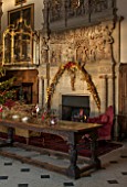 BURTON AGNES HALL, EAST YORKSHIRE: CHRISTMAS  - GREAT HALL, LONG OAK TABLE DECORATED WITH BRANCHES AND GOLDEN HOP - 18TH CENTURY CARVED CHIMNEY PIECE, ORNAMENT