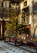 BURTON AGNES HALL, EAST YORKSHIRE: CHRISTMAS  - GREAT HALL, LONG OAK TABLE DECORATED WITH BRANCHES AND GOLDEN HOP - 18TH CENTURY CARVED CHIMNEY PIECE, ORNAMENT, CHRISTMAS TREE