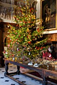 BURTON AGNES HALL, EAST YORKSHIRE: CHRISTMAS  - GREAT HALL, LONG OAK TABLE DECORATED WITH BRANCHES AND GOLDEN HOP - ORNAMENT, CHRISTMAS TREE