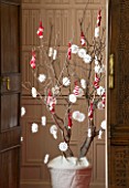 BURTON AGNES HALL, EAST YORKSHIRE: CHRISTMAS - THE JUSTICES ROOM - A SYCAMORE BRANCH DECORATED WITH PAPER SNOWFLAKES AND HAND KNITTED STOCKINGS