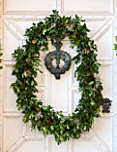 BURTON AGNES HALL, EAST YORKSHIRE: CHRISTMAS - WHITE FRONT DOORWAY WITH HOLLY AND BERRY WREATH MADE BY THE GARDENERS WITH PLANTS FROM ESTATE