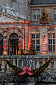 VAUX LE VICOMTE, FRANCE: THE ENTRANCE TO THE PALACE AND MOAT BALLUSTRADE AT CHRISTMAS DECORATED WITH RIBBON BOWS AND CHRISTMAS TREES. TREE, LIGHT, LIGHTING, ILLUMINATION, WINTER