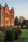 BRODSWORTH HALL, YORKSHIRE: SUNRISE - VIEW ACROSS LAWN TO BORDER OF CLIPPED EVERGREEN TOPIARY WITH HALL BEHIND. VICTORIAN, COUNTRY, GARDEN