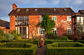 THE FREETH, HEREFORDSHIRE: 15TH CENTURY HOUSE WITH BRICK FACADE, PATH, LAWN, GRASS, SUNSET, EVENING, LIGHT. BOX PARTERRE DESIGNED BY ROBERT MYERS. GARDEN