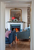 THE FREETH, HEREFORDSHIRE: THE SITTING ROOM. FIRE, FIREPLACE, BOOKCASE WALL PAPER, TEAL SOFAS, WOOD FLOOR, GILT MIRROR, LIVING, ROOM