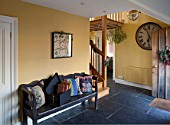 THE FREETH, HEREFORDSHIRE: HALLWAY - SLATE TILES, SLABS, SWEDISH WOODEN BENCH, PRINT ROOM YELLOW FROM FARROW AND BALL PAINTED WALLS, CLOCK, CUSHIONS