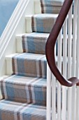 LONDON HOUSE DESIGNED BY JULIE SIMONSEN. DETAIL OF STAIRS WITH WOODEN BANNISTER AND BLUE AND BROWN CHECKED STAIR RUNNER.
