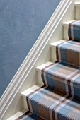 LONDON HOUSE DESIGNED BY JULIE SIMONSEN. DETAIL OF BLUE POLISHED PLASTER WALL WITH BLUE AND BROWN CHECKED STAIR RUNNER