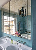 LONDON HOUSE DESIGNED BY JULIE SIMONSEN. VERRE EGLOMISE MIRROR ABOVE DOUBLE BASINS IN BLUE BATHROOM