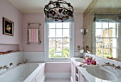 LONDON HOUSE DESIGNED BY JULIE SIMONSEN. THE PINK BATHROOM WITH PANELLED BATH AND DOUBLE BASINS WITH DUTCH ANTIQUE CHANDELIER.