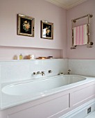 LONDON HOUSE DESIGNED BY JULIE SIMONSEN. PINK BATHROOM. PANELLED BATH WITH TOWEL RAIL AND ANTIQUE FLOWER PRINTS DISPLAYED ON WALL