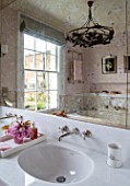 LONDON HOUSE DESIGNED BY JULIE SIMONSEN. PINK BATHROOM. CHERRY BLOSSOM ON TRAY WITH FAKE VERRE EGLOMISE MIRROR AND MARBLE SINK SURROUND