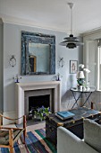 LONDON HOUSE DESIGNED BY JULIE SIMONSEN. THE LIVING ROOM DECORATED IN SHADES OF BLUE WITH NEW SANDSTONE FIREPLACE SURROUND. DISTRESSED BLUE MIRROR AND VINTAGE TRUNK USED AS COFFEE TABLE.