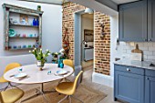 LONDON HOUSE DESIGNED BY JULIE SIMONSEN. MORNING ROOM ADJACENT TO KITCHEN WITH CIRCULAR TABLE AND CONTEMPORARY YELLOW CHAIRS. AZURE BLUE KITCHEN BY LAURENCE PIDGEON
