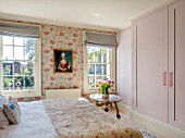 LONDON HOUSE DESIGNED BY JULIE SIMONSEN. GUEST BEDROOM WITH PAINTING OF YOUNG GIRL FOUND AT PARISIAN ANTIQUES DEALER. JULIE DECORATED THE WHOLE ROOM AROUND HER. WALLPAPER BY OSBORNE & LITTLE. QUILTED ANTIQUE WELSH COVERLET. CONTEMPORARY RESIN HANDLES ON WARDROBE FROM SHOP DECO