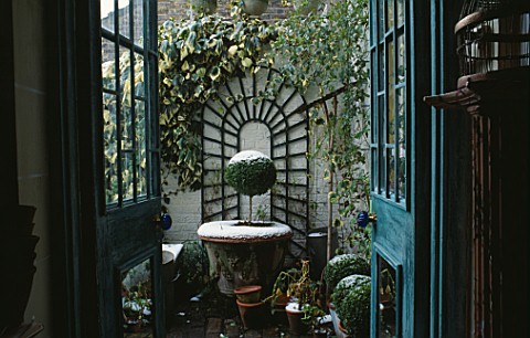 VIEW_THROUGH_BACK_DOORFRENCH_WINDOWS_ONTO_BRICK_TERRACE_OF_SMALL_TOWN_GARDEN_WITH_ARCHED_TRELLIS__HE