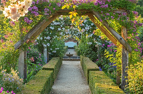 MOTTISFONT_ABBEY_HAMPSHIRE_WOODEN_PERGOLA_PATHS_WHITE_WOODEN_BENCH_ROSES_VISTA_FORMAL_COUNTRY_GARDEN