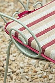 THE CONIFERS, OXFORDSHIRE: GRAVEL, GARDEN, COTSWOLDS, DETAIL OF CHAIR WITH CUSHION. PINK, GREEN, COURTYARD