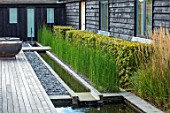 PRIVATE GARDEN, SURREY: DESIGNER ANTHONY PAUL: DECKED GARDEN, DECKING, FORMAL, SMALL, ENGLISH, COUNTRY, GRANITE RILL, WATER, POND, POOL, SPOUT, PEBBLES, HEDGE, EQUISETUM HYEMALE