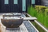 PRIVATE GARDEN, SURREY: DESIGNER ANTHONY PAUL: DECKED GARDEN, CONTAINERS, WATERLILIES. DECKING, ROUND, CIRCULAR, FORMAL, SMALL, ENGLISH, COUNTRY, RILL, EQUISETUM HYEMALE, HORSETAIL