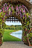 LEEDS CASTLE, KENT: FLORAL DECORATION, FLOWERS, ORCHIDS ON DRAWBRIDGE GATE, BARBICAN RUINS, FLORAL DESIGN BY TRACY ROWBOTTOM OF COUNTRY BASKETS