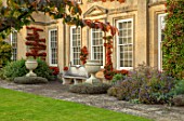 BOURTON HOUSE GARDEN, GLOUCESTERSHIRE: LAWN, HOUSE, STONE , AUTUMN, FALL, SEPTEMBER, ENGLISH, LATE, SUMMER, TRAINED PYRACANTHA ON WALL, URNS, CONTAINERS, PARROTIA PERSICA