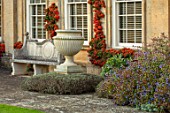 BOURTON HOUSE GARDEN, GLOUCESTERSHIRE: LAWN, HOUSE, STONE , AUTUMN, FALL, SEPTEMBER, ENGLISH, LATE, SUMMER, TRAINED PYRACANTHA ON WALL, URNS, CONTAINERS, CERATOSTIGMA