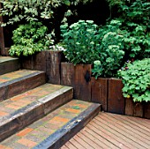 TIMBER DECKING LEADING TO BRICK STEPS  EDGED WITH WOODEN SLEEPERS. DESIGNER: VIC SHANLEY