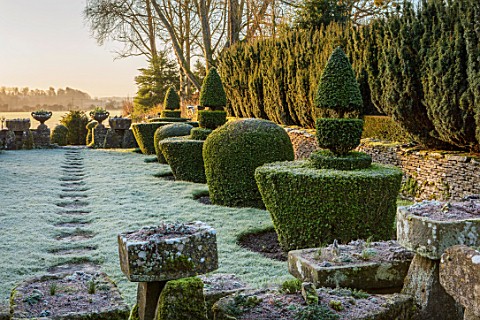 RODMARTON_MANOR_GLOUCESTERSHIRE_WINTER_FEBRUARY__FROST_PATH_TROUGHERY_STONE_URNS_CONTAINERS_DAWN_LIG
