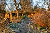 RODMARTON MANOR, GLOUCESTERSHIRE, WINTER - PATH THROUGH THE SPRING BORDER IN FROST. ENGLISH, COUNTRY, GARDEN, FEBRUARY