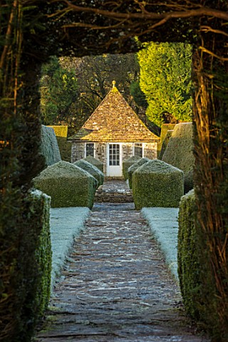 RODMARTON_MANOR_GLOUCESTERSHIRE_WINTER__PATH_WITH_STONE_SUMMERHOUSE_AND_YEW_TOPIARY_HEDGES_IN_FROST_
