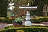 THENFORD GARDENS & ARBORETUM, NORTHAMPTONSHIRE: KNOT GARDEN AND FOUNTAIN WITH CONTAINERS PLANTED WITH GALANTHUS JAMES BACKHOUSE AND OPHIOPOGON PLANISCAPUS NIGRESCENS