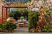ASCOT SPRING GARDEN SHOW: GARDEN DESIGNED BY KATE GOULD: TABLE, CHAIRS, TERRACOTTA CONTAINER, CORTEN STEEL PERGOLA, SCREENS, SCREENING, DINING, FORMAL, URBAN, SMALL, CHERRY, PRUNUS