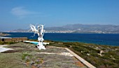 ANTIPAROS, GREECE, DESIGNER THOMAS DOXIADIS: VILLA GARDEN WITH WHITE METAL OLIVE TREE SCULPTURE LOOKING OUT TO SEA