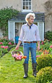 THE OLD PARSONAGE, DORSET: OWNER CHARLIE MCCORMICK IN HIS FRONT GARDEN WITH TRUG OF PICKED TULIPS