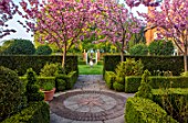 MITTON MANOR, STAFFORDSHIRE: PATH, TERRACOTTA CONTAINER, STEPS, CHERRY BLOSSOM, OBELISK, CLIPPED, TOPIARY, SPRING, PRUNUS, BLOSSOM, PINK, FLOWERS, SYMMETRY, HEDGES, HEDGING