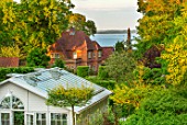 CLAUS DALBY GARDEN, DENMARK: VIEW TO SEA WITH TREES, GREENHOUSE, GARDEN BUILDING, CONSERVATORY