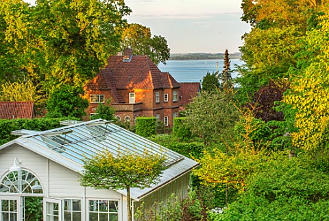 CLAUS_DALBY_GARDEN_DENMARK_VIEW_TO_SEA_WITH_TREES_GREENHOUSE_GARDEN_BUILDING_CONSERVATORY