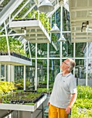 CLAUS DALBY GARDEN, DENMARK: CLAUS DALBY IN ONE OF HIS GREENHOUSES FILLED WITH SEEDLINGS