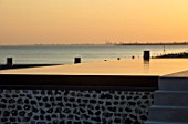 SEASIDE GARDEN DESIGNED BY ANTHONY PAUL: INFINITY SWIMMING POOL IN EVENING WITH VIEW TO SEA AND PORTSMOUTH