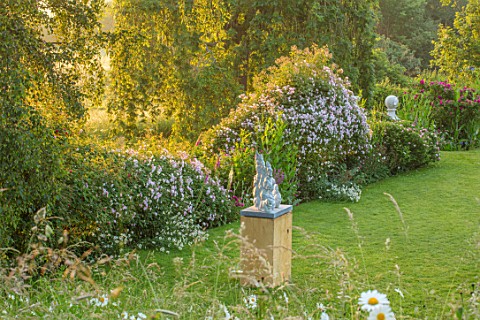 ASTHALL_MANOR_OXFORDSHIRE_LAWN_WITH_ROSES_HEDGE_AND_MEADOW_BEYOND_SCULPTURE_SOGNO_DALTEZZA_BY_ROB_GO
