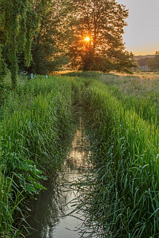 ASTHALL_MANOR_OXFORDSHIRE_SUNSET_OVER_THE_MILL_STREAM_IN_THE_WINDRUSH_VALLEY_WATER_SUMMER_COUNTRYSID