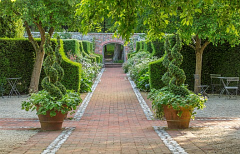 WORMSLEY_BUCKINGHAMSHIRE_FLINT_AND_BRICK_PATH_WALLED_GARDEN__TERRACOTTA_CONTAINERS_BOX_SPIRALS_MALUS