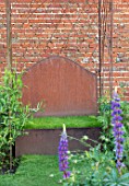 THE WALLED GARDEN AT COWDRAY, WEST SUSSEX: RUSTY METAL SEAT, BENCH, TURF, WALL, PLACE TO SIT, LUPINS, ENGLISH, COUNTRY, GARDENS