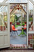 THE WALLED GARDEN AT COWDRAY, WEST SUSSEX: ENGLISH, COUNTRY, GARDEN, INSIDE OF GREENHOUSE, ORANGE CHAIR, TABLE, GLASSHOUSE