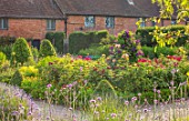 THE WALLED GARDEN AT COWDRAY, WEST SUSSEX: ENGLISH, COUNTRY, GARDEN, BORDERS OF RED, FLOWERED ROSES, SUMMER, BOX EDGED, BEDS, BUXUS, CLEMATIS, PATHS
