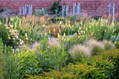 WYNYARD HALL, COUNTY DURHAM: WALLED ROSE GARDEN. BORDERS, SUMMER, JUNE, YELLOW, KNIPHOFIA, STIPA TENUISSIMA, ROSES, WOODEN, TRELLIS, SUPPORTS